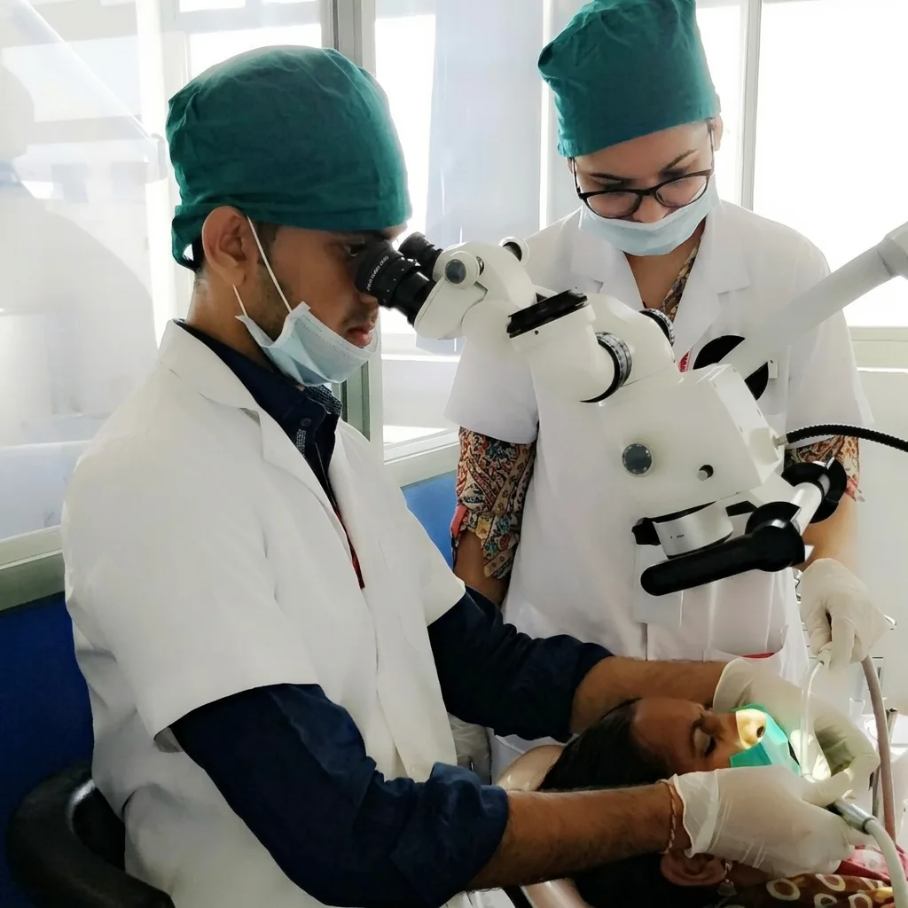 Dr. Chinmay H. Patel treating a patient under a dental operating microscope in Mehsana